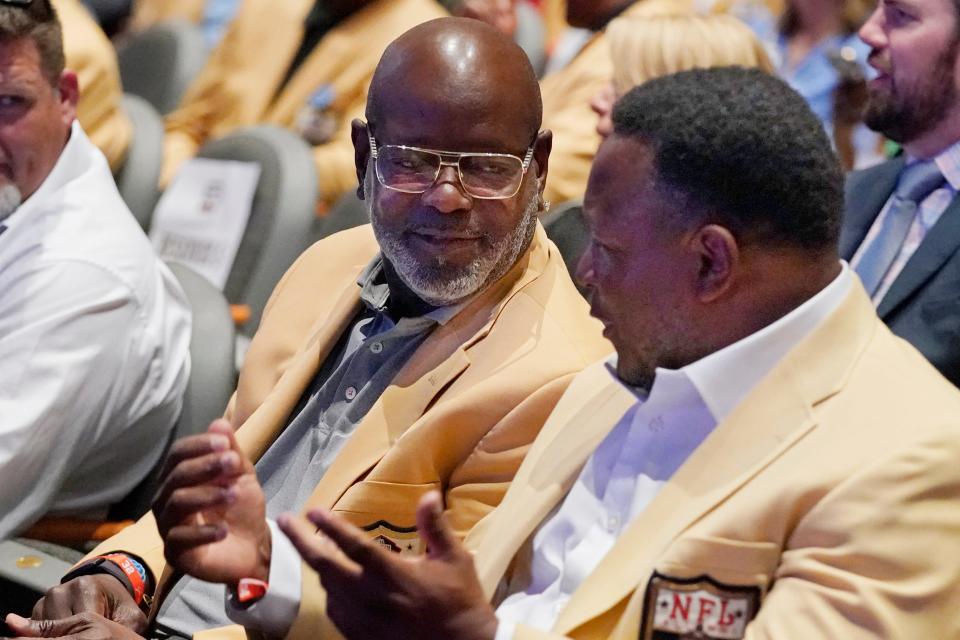 Pro Football Hall of Famers Emmit Smith, left, and Barry Sanders, right, talk before a tribute to the late Jim Brown Thursday in Canton.