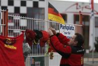 A fan fixes a flag marking the 45th birthday of seven-times former Formula One world champion Michael Schumacher, to a fence outside Schumacher's cart racing track, in the western city of Kerpen January 3, 2014. REUTERS/Ina Fassbender