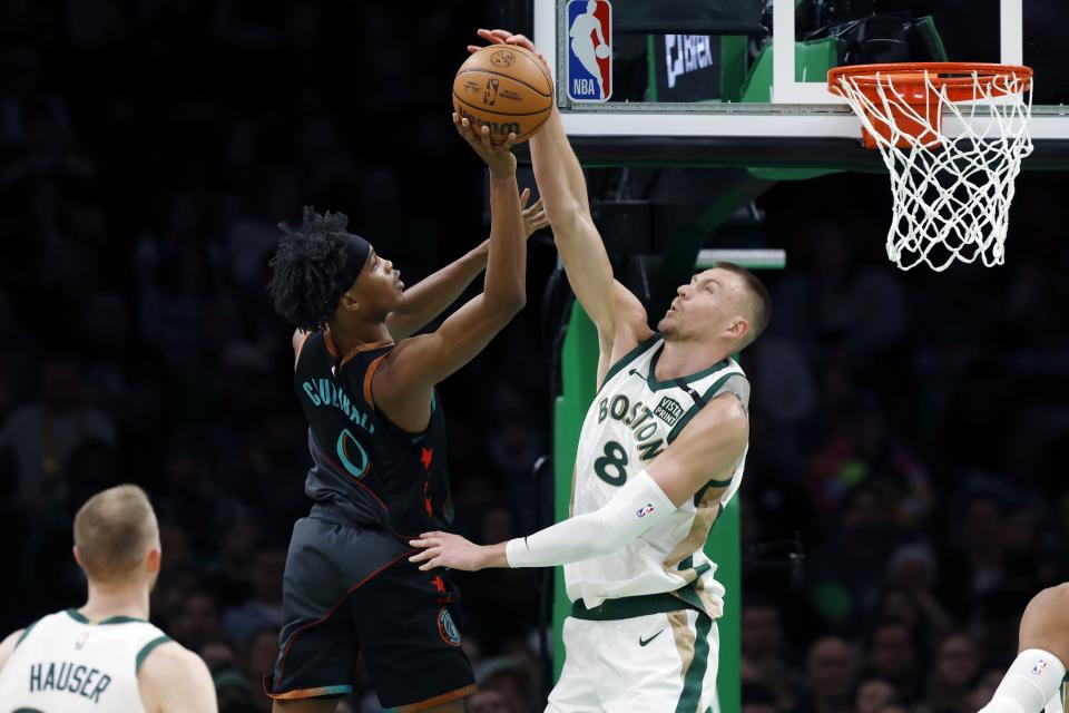 Boston Celtics' Kristaps Porzingis (8) blocks a shot by Washington Wizards' Bilal Coulibaly (0) during the first half of an NBA basketball game Friday, Feb. 9, 2024, in Boston. (AP Photo/Michael Dwyer)