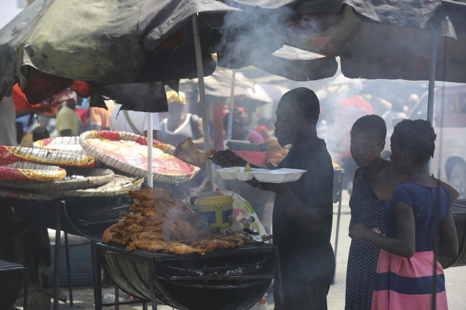 A vendor sells grilled chicken to customers in Port-au-Prince, Haiti, Monday, April 8, 2024. (AP Photo/Odelyn Joseph)