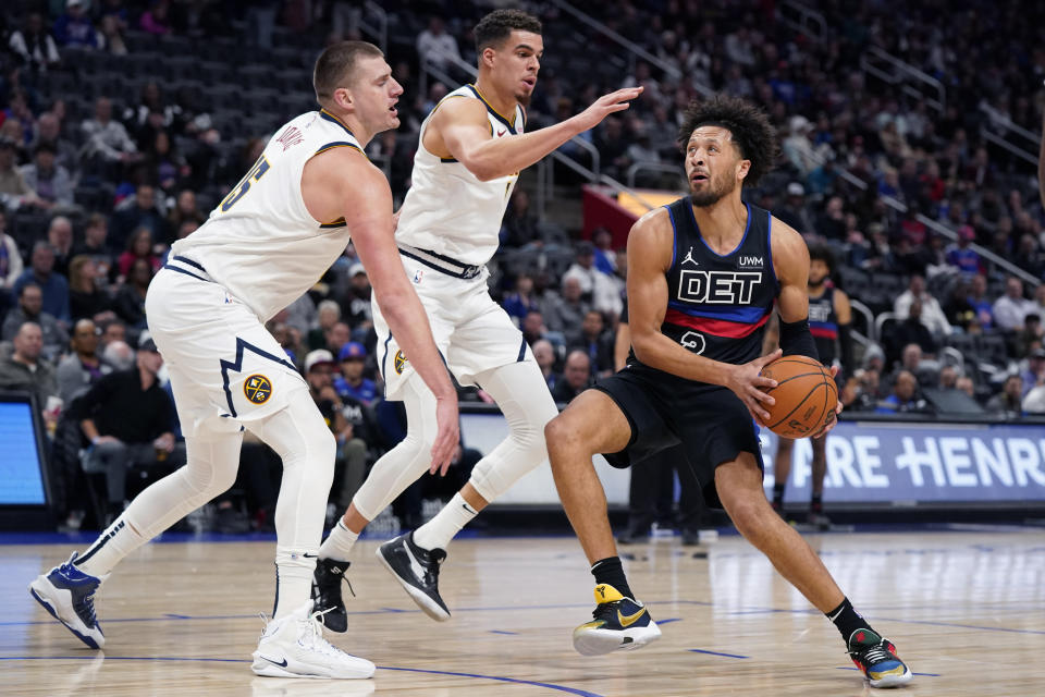 Detroit Pistons guard Cade Cunningham (2) is defended by Denver Nuggets center Nikola Jokic (15) and forward Michael Porter Jr. (1) during the first half of an NBA basketball game, Monday, Nov. 20, 2023, in Detroit. (AP Photo/Carlos Osorio)