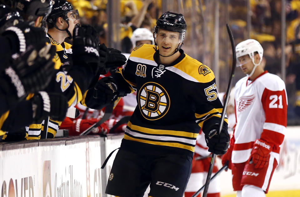 Boston Bruins' Justin Florek is congratulated at the bench after scoring a goal as Detroit Red Wings' Tomas Tatar (21) skates to the bench during the first period of Game 2 of a first-round NHL hockey playoff series in Boston Sunday, April 20, 2014. (AP Photo/Winslow Townson)