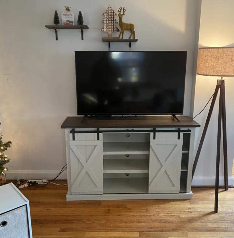 Reviewer's photo of the white sliding barn door stand with tv perched on top