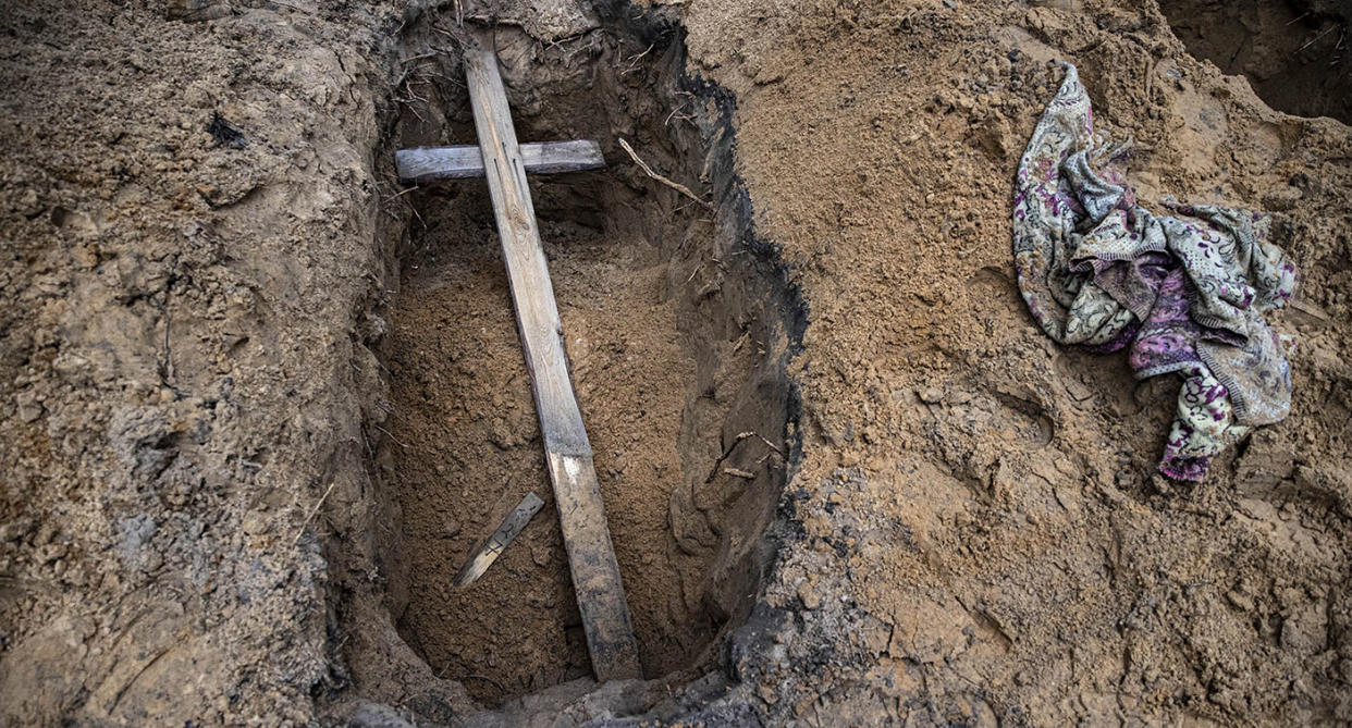 A wooden cross lies in a shallow grave in Izyum, Ukraine.