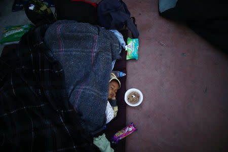 A child traveling with a caravan of migrants from Central America sleeps near the San Ysidro checkpoint after a small group of fellow migrants entered the United States border and customs facility, where they are expected to apply for asylum, in Tijuana, Mexico April 30, 2018. REUTERS/Edgard Garrido