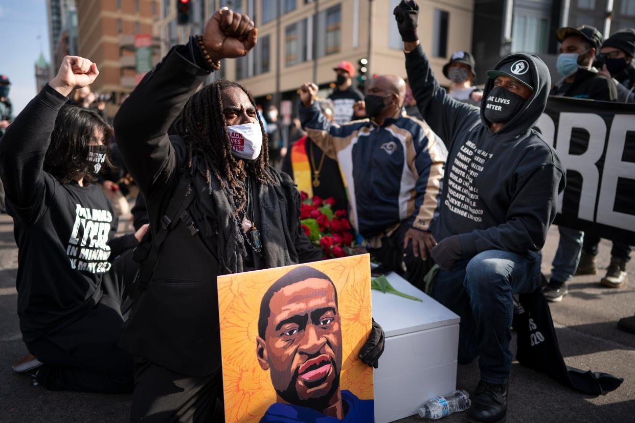 <p>Cortez Rice, left, of Minneapolis, sits with others in the middle of Hennepin Avenue on Sunday, March 7, 2021, in Minneapolis, Minn., to mourn the death of George Floyd a day before jury selection is set to begin in the trial of former Minneapolis officer Derek Chauvin, who is charged in Floyd's death. (Jerry Holt/Star Tribune via AP)</p> (© 2021 Jerry Holt/Star Tribune)