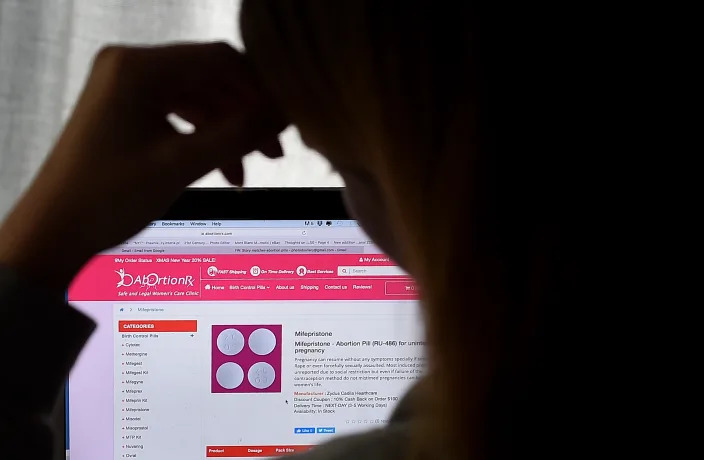 Sally, whose name has been changed to protect her privacy, looks at an abortion pill for unintended pregnancy from Mifepristone on May 8, 2020, in Arlington, Virginia. (Photo by Olivier DOULIERY / AFP) 