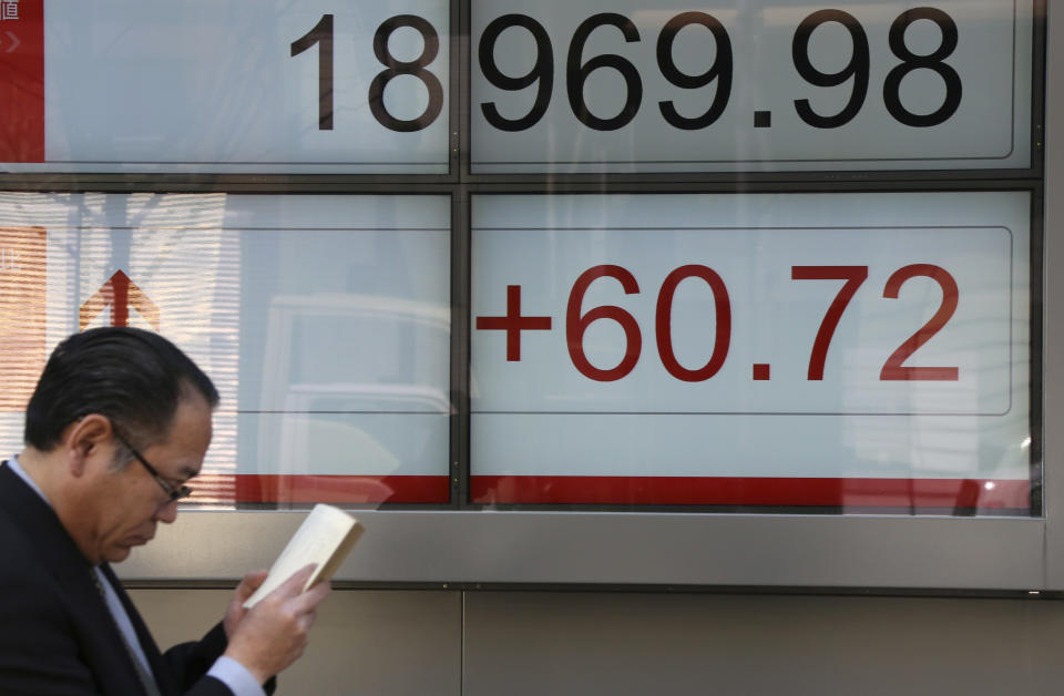 A man walks by an electronic stock board of a securities firm in Tokyo, Monday, April 3, 2017. Asian markets were mostly higher Monday, cheered by a positive report on the Japanese economy, as players awaited a meeting between U.S. and Chinese leaders later in the week. (AP Photo/Koji Sasahara)