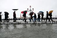 FILE PHOTO: People walk on a catwalk in the flooded St. Mark's Square in Venice, Italy