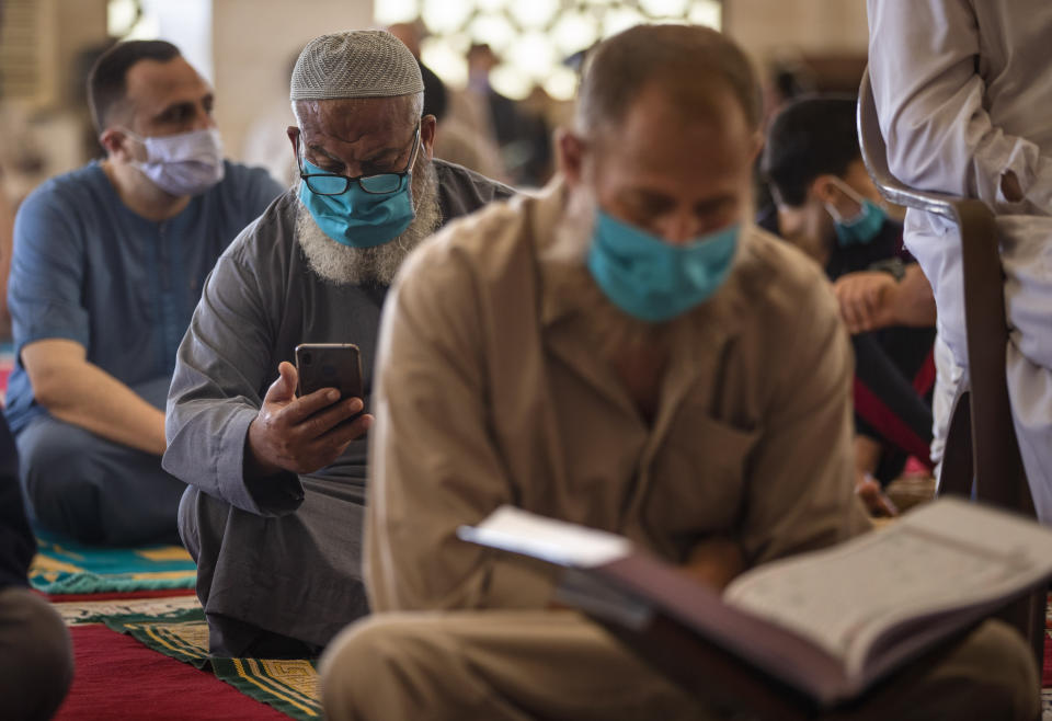 Palestinians wearing face masks read the Quran as they attend the last Friday noon Prayer of the holy month of Ramadan, in a mosque in Gaza City, Friday, May. 22, 2020. After nearly two months of closure due to the coronavirus, Gaza's Hamas rulers decided to partially reopen mosques for the Friday noon prayer. (AP Photo/Khalil Hamra)