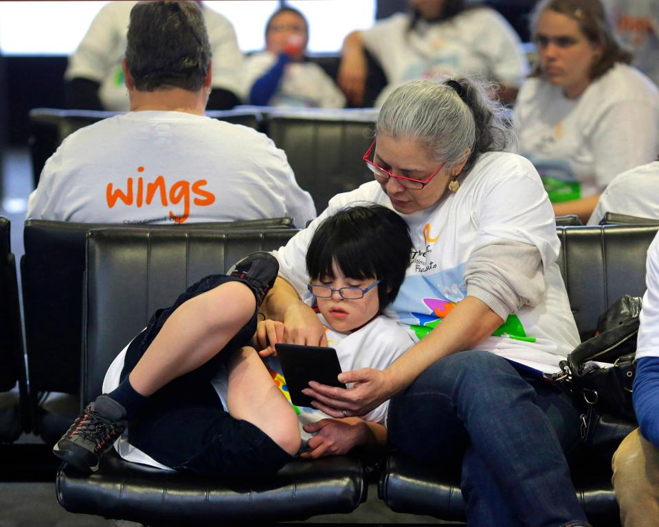 Monica Sanjur reads with her son, Patxi Uy, 11, as they wait at their boarding gate at Baltimore-Washington International Thurgood Marshall Airport, on Dec. 6, 2014, during Wings for Autism, an airport rehearsal for children with autism spectrum disorders, their families and aviation officials.