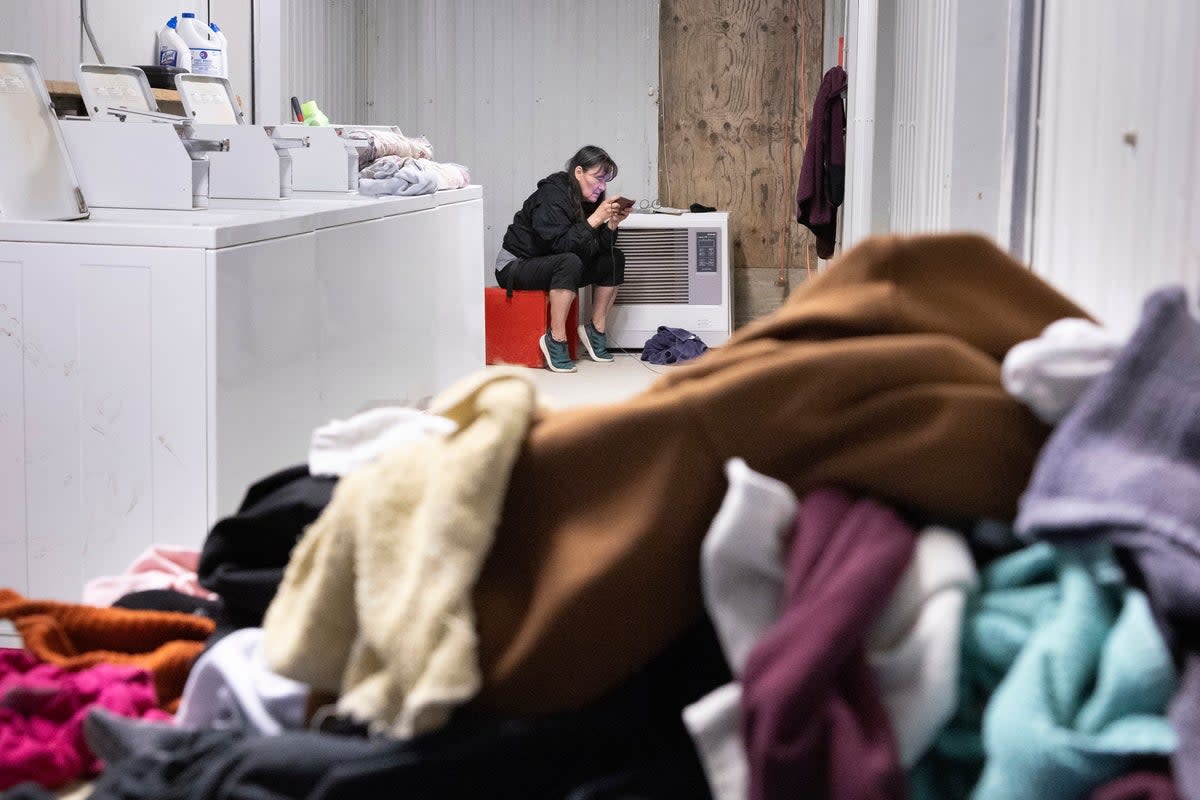 File: A woman uses a cell phone while keeping watch over washing machine  (Copyright 2023 The Associated Press. All rights reserved)