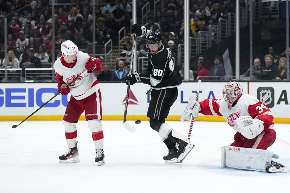 Los Angeles Kings center Pierre-Luc Dubois (80) attempts to redirect the puck against Detroit Red Wings goaltender Alex Lyon (34) as Red Wings left wing Lucas Raymond (23) watches during the second period of an NHL hockey game Thursday, Jan. 4, 2024, in Los Angeles. (AP Photo/Jae C. Hong)