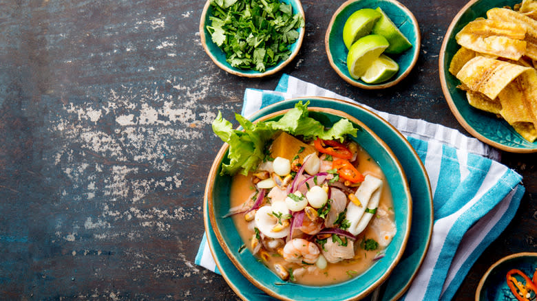 bowls of ceviche, limes, cilantro, and tortilla chips