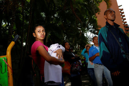 A woman carrying a baby queues as she trys to buy food outside a supermarket in Caracas, Venezuela March 10, 2017. REUTERS/Carlos Garcia Rawlins