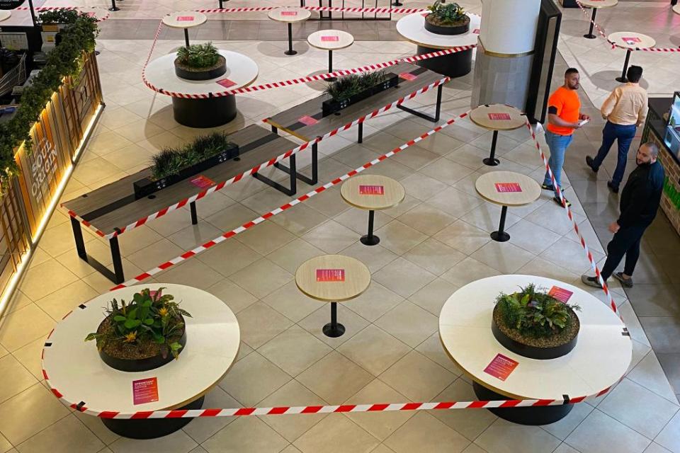 Customers wait for take-away meals next to roped-off dining tables as restaurants only cater for take-away in Sydney on March 26, 2020, due to restrictions to stop the spread of the worldwide COVID-19 coronavirus outbreak. (Photo by Saeed KHAN / AFP) (Photo by SAEED KHAN/AFP via Getty Images)