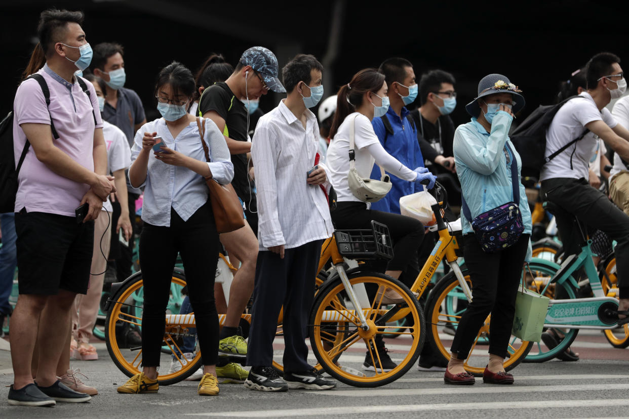 People wearing protective face masks to help curb the spread of the new coronavirus wait to cross a street in Beijing, Monday, June 22, 2020. A Beijing government spokesperson said the city has contained the momentum of a recent coronavirus outbreak that has infected a few hundreds of people, after the number of daily new cases fell to single digits. (AP Photo/Andy Wong)