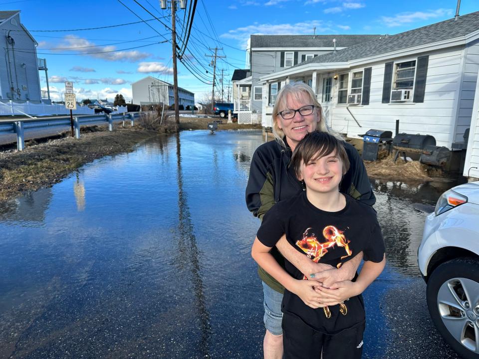 Emma Perry and her grandson Liam pose in Perry's driveway, which was flooded due to high tides at Hampton Beach.