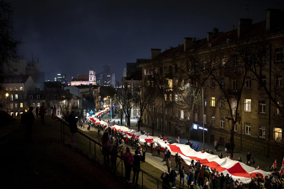 People carry a giant historical flag of Belarus during a celebration 103rd anniversary of the declaration of the Belarusian People's Respublic, in Vilnius, Lithuania, Thursday, March 25, 2021. Freedom Day is an unofficial holiday in Belarus celebrated on 25 March to commemorate the declaration of independence by the Belarusian Democratic Republic on that date in 1918.(AP Photo/Mindaugas Kulbis)