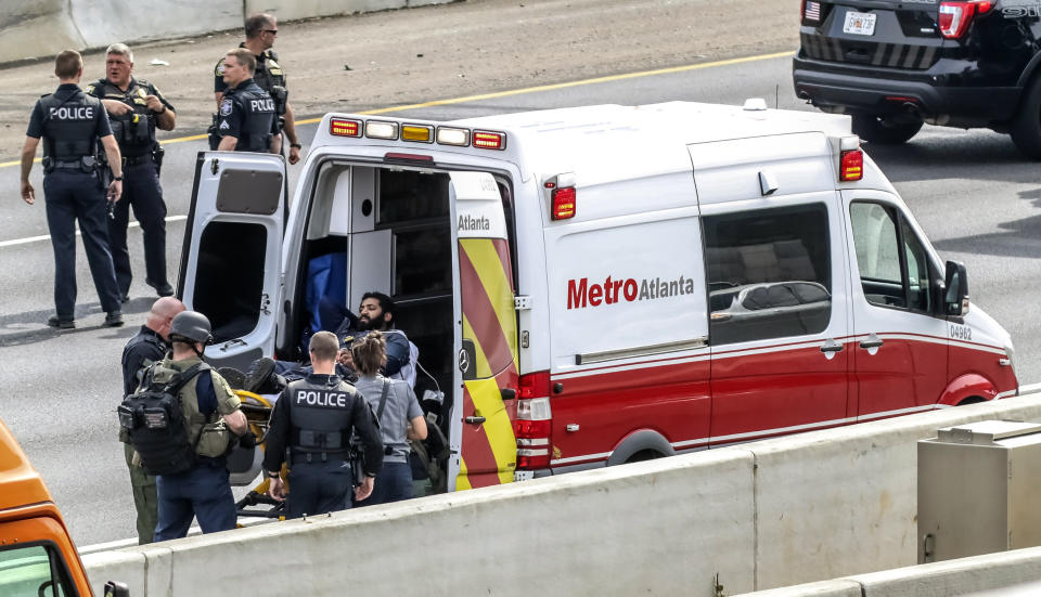 Police officers place a man they detained into an ambulance following a standoff along the southbound lanes of Interstate 75, Friday, March 29, 2019, near Marietta, Ga., northwest of Atlanta. Marietta police said an armed driver had stopped on the freeway and wasn't cooperating with officers. Police had followed the vehicle to I-75 since it matched the description from an armed robbery nearby. (John Spink/Atlanta Journal-Constitution via AP)