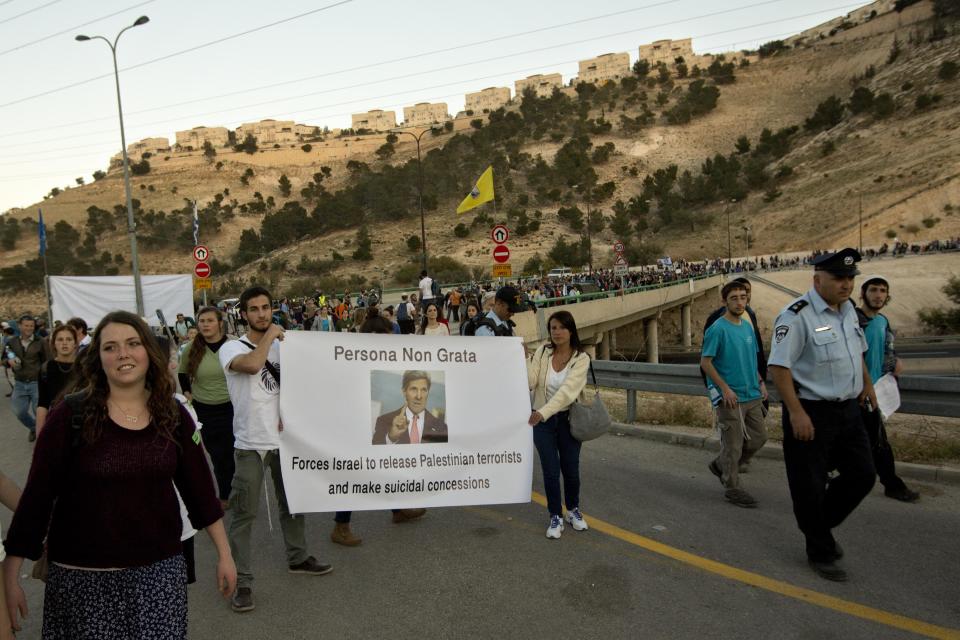 Israelis hold a sign depicting U.S. Secretary of State John Kerry during a march from the West Bank settlement of Maaleh Adumim to the E-1 area on the eastern outskirts of Jerusalem, Thursday, Feb. 13, 2014. Israel planned construction in the area E-1, or East 1, but froze under the international pressure in 2009. The construction in the area would effectively separate Palestinians in east Jerusalem from the West Bank. (AP Photo/Sebastian Scheiner)