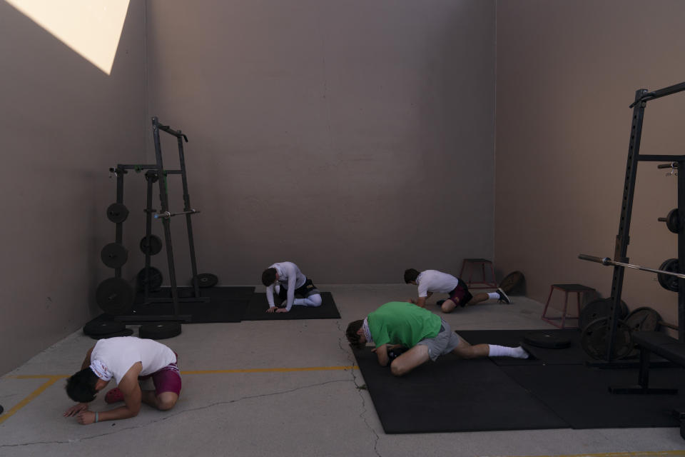 El Modena players stretch at a school gym temporarily set up at outdoor racquetball courts before the team's high school football game with El Dorado in Orange, Calif., Friday, March 19, 2021. (AP Photo/Jae C. Hong)