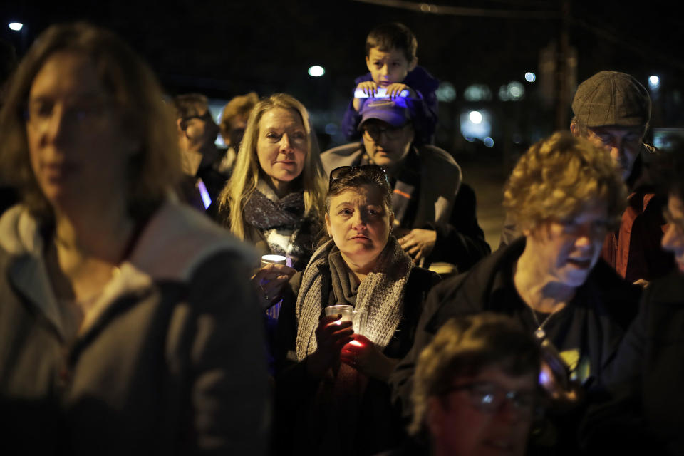 People watch as a menorah is lighted outside the Tree of Life Synagogue on the first night of Hanukkah, Sunday, Dec. 2, 2018 in the Squirrel Hill neighborhood of Pittsburgh. A gunman shot and killed 11 people while they worshipped Saturday, Oct. 27, 2018 at the temple. (AP Photo/Gene J. Puskar)