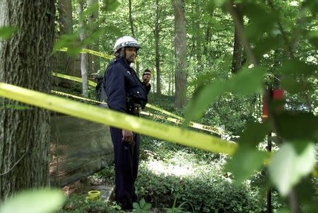 A Washington Metropolitan Police Officer stands behind police lines in Rock Creek Park in Washington in this file photo, May 22, 2002. REUTERS/William Philpott