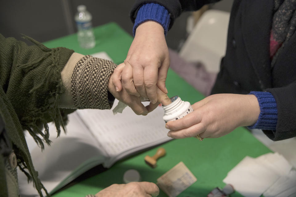 An Algerian voter dips her finger in ink to register her fingerprint after voting, Thursday, Dec.12, 2019, at the Algerian consulate in Marseille, southern France. Five candidates have their eyes on becoming the next president of Algeria in Thursday's contentious election boycotted by a massive pro-democracy movement. (AP Photo/Daniel Cole)