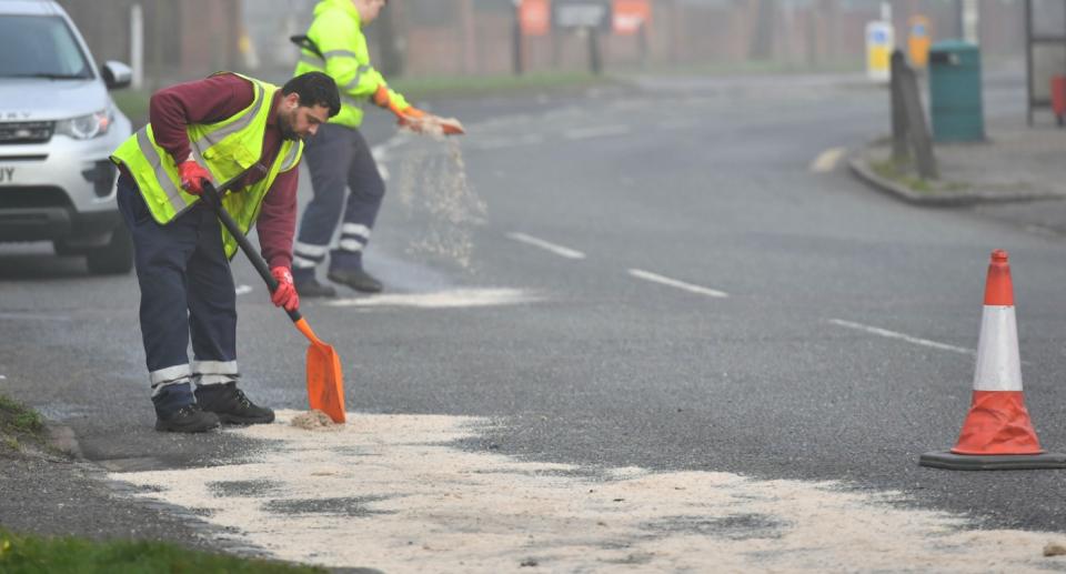 Workers spreading sand on Footscray Road in Eltham where the man and woman died (PA)