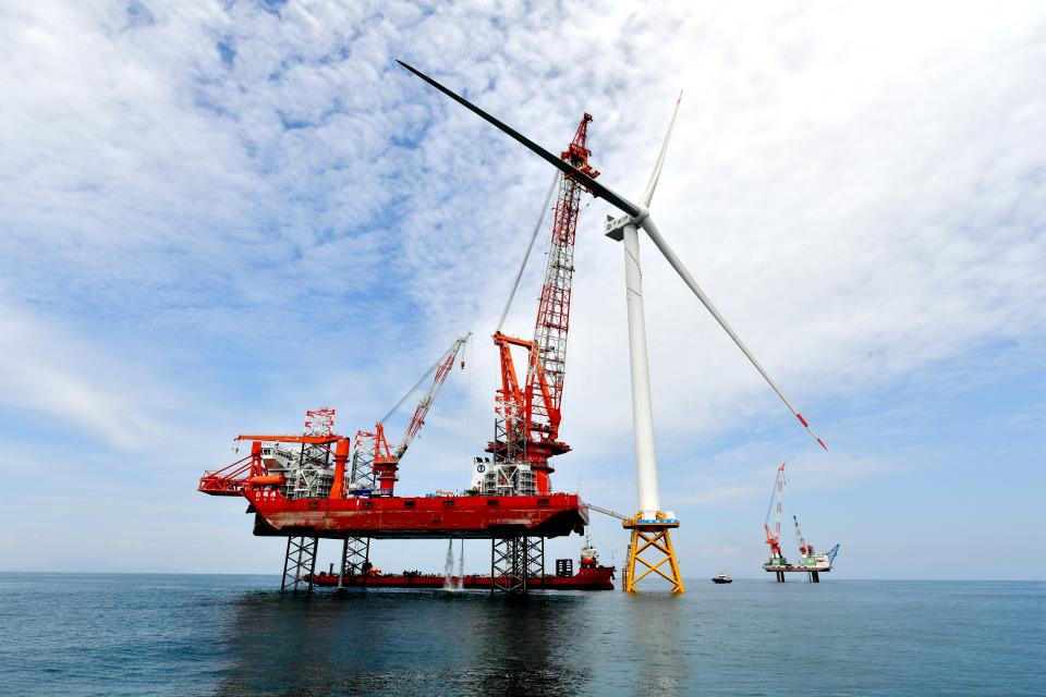 a crane installs a massive wind turbine in the water