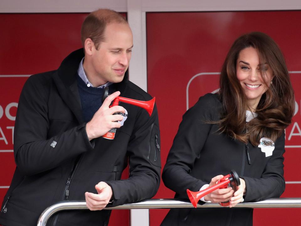 Prince William blows an air horn at Kate Middleton while cheering on marathon runners.