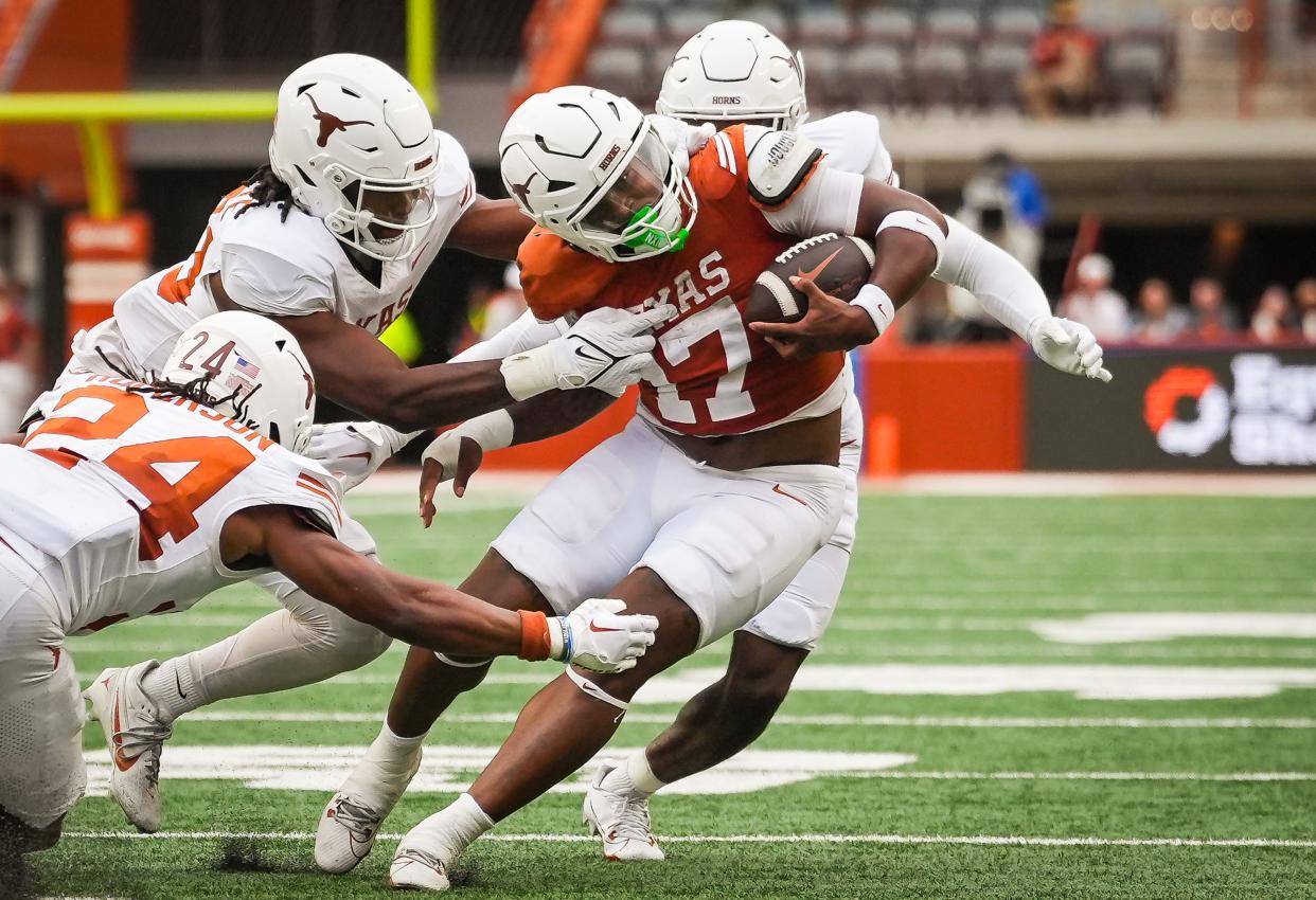 Texas running back Savion Red is tackled by three defenders during the fourth quarter of Saturday's Orange-White spring game at Royal-Memorial Stadium.