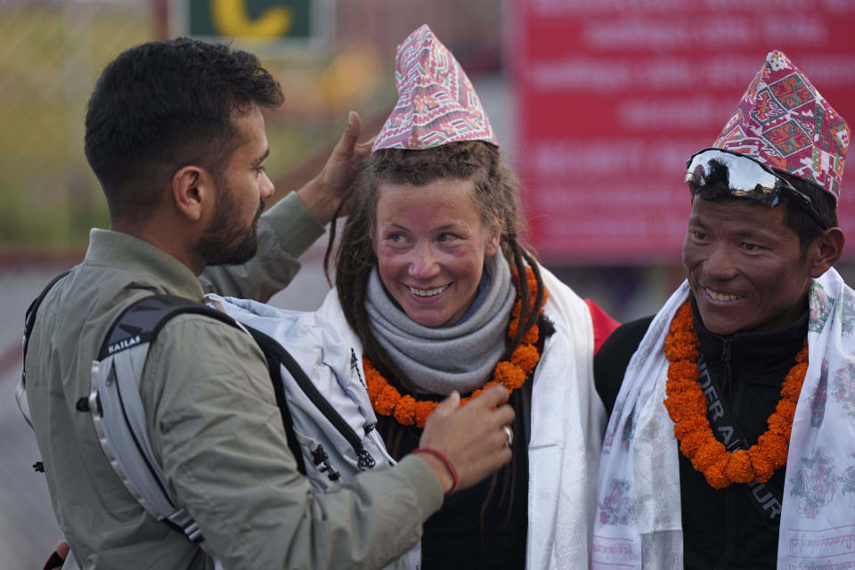 Norwegian climber Kristin Harila, 37, center, smiles as a man adjusts a traditional Nepalese cap presented to her after she arrived in Kathmandu, Nepal, Thursday, May 4, 2023. Harila who just became the fastest female climber to scale the 14 highest mountains in the world is now aiming to become the fastest person to complete the feat, beating a record set by a male climber in 2019. (AP Photo/Niranjan Shrestha)