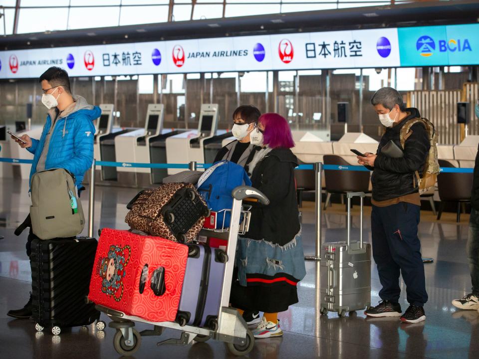 Travelers wearing face masks line up near the Japan Airlines check-in counters at Beijing Capital International Airport in Beijing, Thursday, Jan. 30, 2020. China counted 170 deaths from a new virus Thursday and more countries reported infections, including some spread locally, as foreign evacuees from China's worst-hit region returned home to medical observation and even isolation. (AP Photo/Mark Schiefelbein)