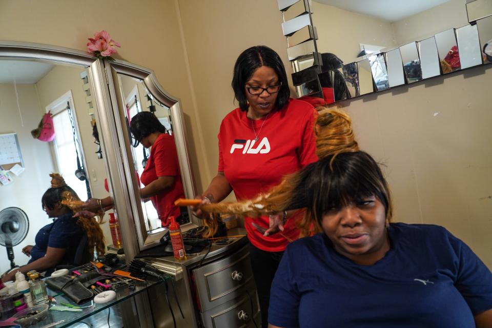 Detroit resident Nyosha Fowler, left, fixes a hairpiece for her friend Tyese White. Fowler lost her job as a truck driver, her apartment and her car after a botched plastic surgery procedure that hospitalized her.