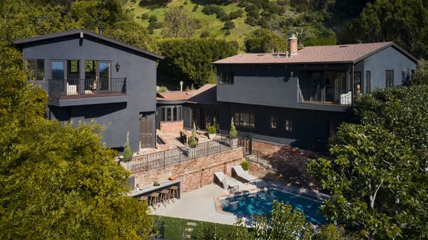 The home's handsome dark gray facade pops against the red brick lining the outdoor patio.