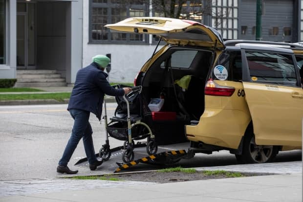 A taxi cab loads a walker into his wheelchair accessible van in Vancouver on Jan. 30, 2020.