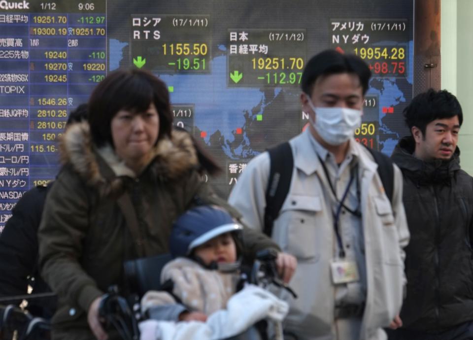 <em>Unos transeúntes pasan por delante de una pantalla que muestra la cotización del índice Nikkei de la Bolsa de Tokio el 12 de enero de 2017 en la capital japonesa (AFP | Kazuhiro Nogi)</em>