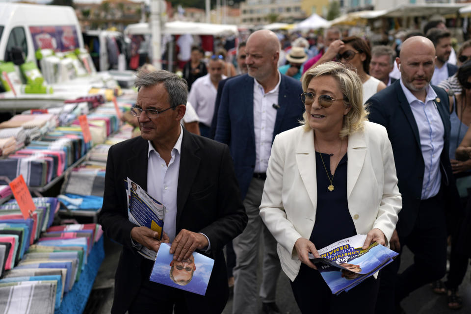 FILE - In this June 17, 2021, file photo, far-right leader Marine le Pen, right, and local candidate Thierry Mariani, left, campaign at an open air market of Six-Fours-les-Plages, southern France. Le Pen’s once-ascendant far-right party is struggling ahead of runoff elections for France's regional leadership. Its best chance of victory is Mariani, a European lawmaker who meets regularly with Syrian dictator Bashar al-Assad and celebrated Russia’s annexation of Crimea. (AP Photo/Daniel Cole, File)