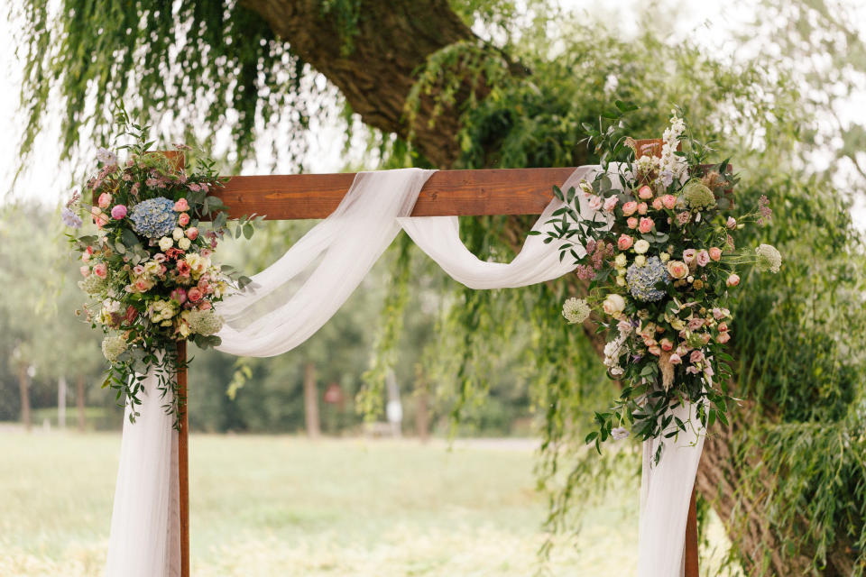 Wedding arch decorated with flowers and greenery.