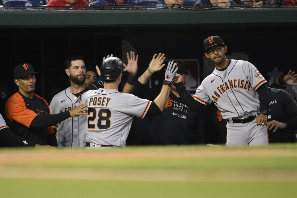 San Francisco Giants' Buster Posey (28) is congratulated in the dugout after his home run during the fourth inning of a baseball game against the Washington Nationals, Friday, June 11, 2021, in Washington. (AP Photo/Nick Wass)