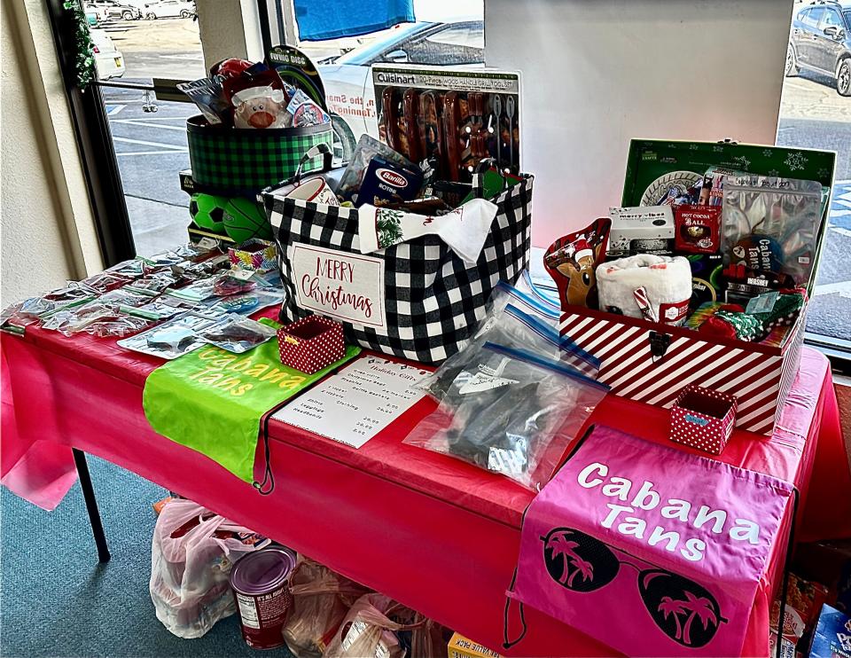 A table inside Cabana Tans is loaded down with gift baskets that will be raffled to raise money for the Four Corners Home for Children, while below rests a fresh pile of donations to the home dropped off Friday by the Prime Time 4H organization.