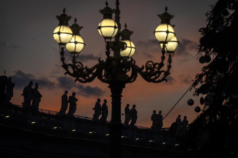 Statues of the Saints are silhouetted at sunset on top of the Colonnades of St. Peter's Square at the Vatican, Tuesday, Jan. 3, 2023. The Vatican announced that Pope Benedict died on Dec. 31, 2022, aged 95, and that his funeral will be held on Thursday, Jan. 5, 2023. (AP Photo/Ben Curtis)