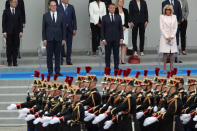 France's President Emmanuel Macron, center, and his wife Brigitte Macron, right, with France's Prime Minister Jean Castex, left, look at the Bastille Day military parade, Tuesday, July 14, 2020 in Paris. France are honoring nurses, ambulance drivers, supermarket cashiers and others on its biggest national holiday Tuesday. Bastille Day's usual grandiose military parade in Paris is being redesigned this year to celebrate heroes of the coronavirus pandemic. (AP Photo/Francois Mori)