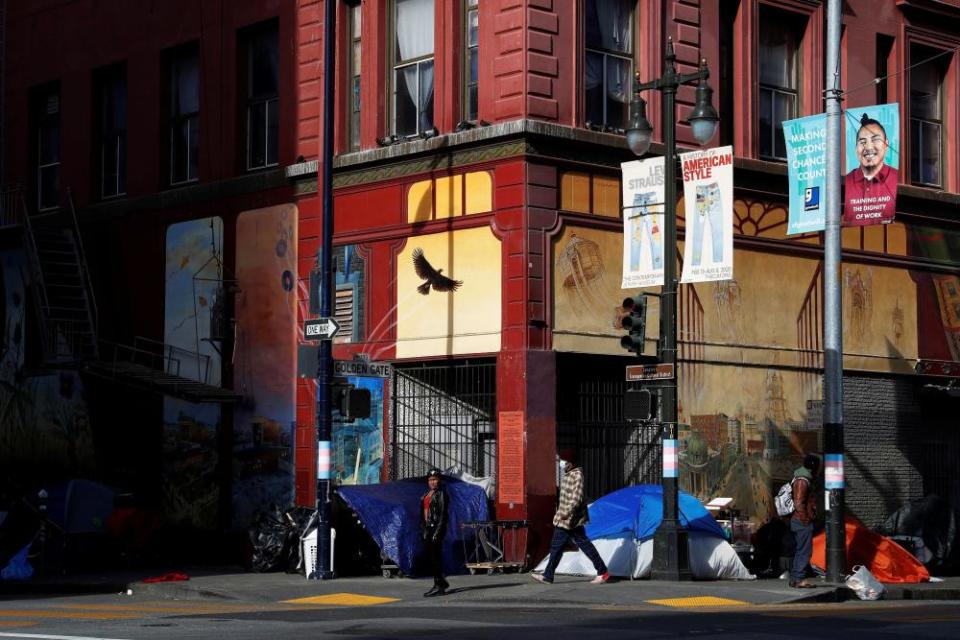 Pedestrians walk by homeless encampments in the Tenderloin.