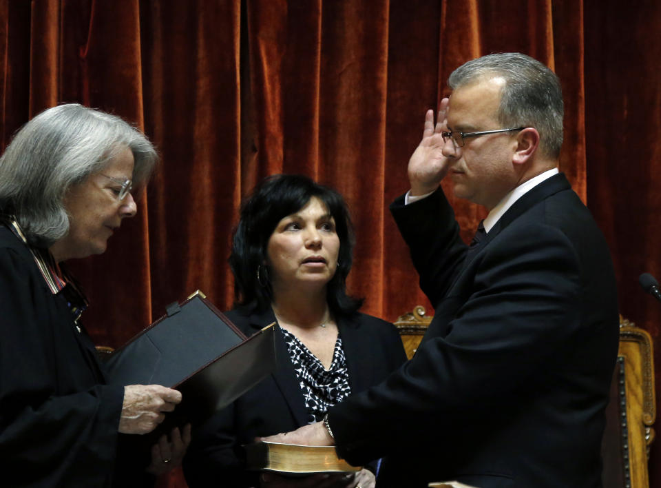 Democrat Nicholas Mattiello, of Cranston, R.I., accompanied by his wife, Mary Ann, is sworn in as the new Speaker of the Rhode Island House of Representatives at the Statehouse in Providence, Tuesday, March 25, 2014. Mattiello was elected after the abrupt resignation of Gordon Fox, one of the most powerful figures in state government, after his home and Statehouse office were raided as part of a criminal probe. (AP Photo/Elise Amendola)