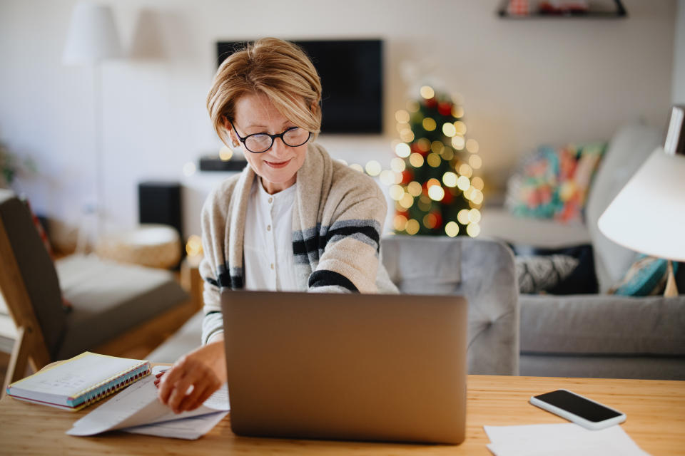 tax Senior woman working on home finance. Mature woman checking bills at home. Older woman checking pension approval certificate with laptop at home.