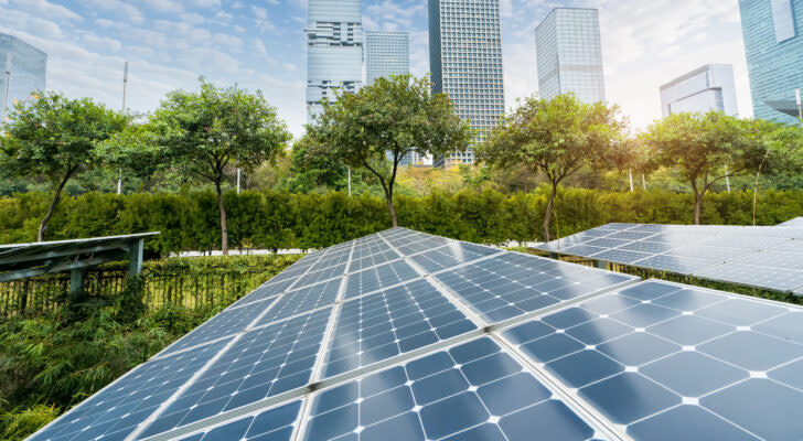 An image of solar panels with cityscape of a modern city