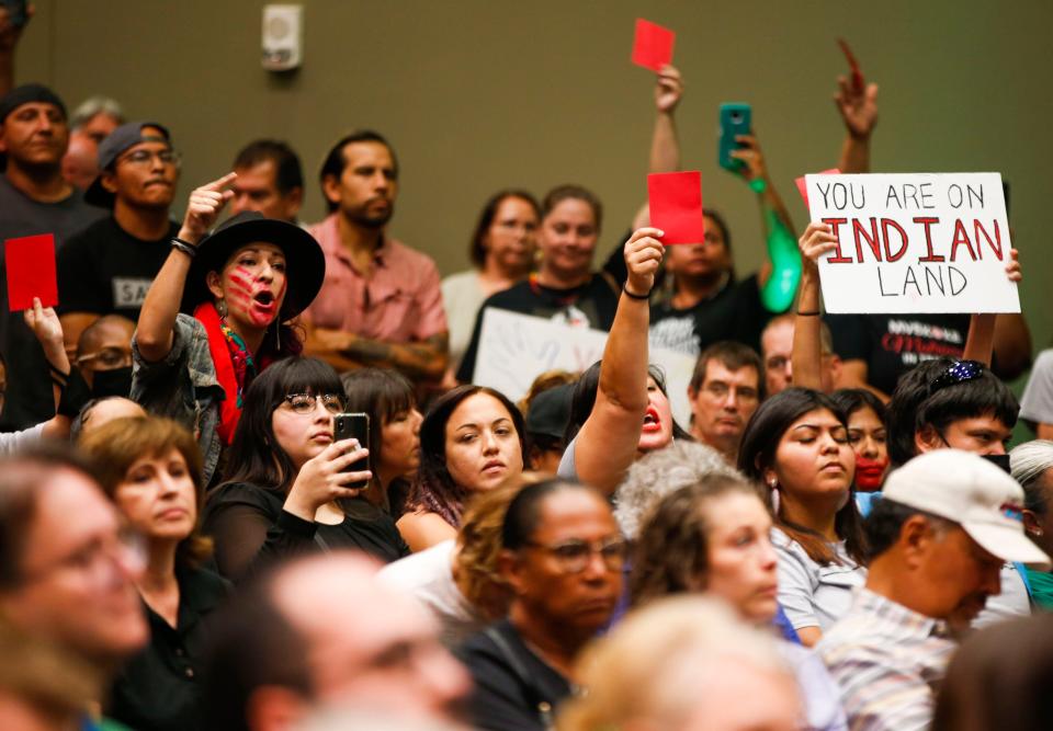 Brittany Dias counters claims made by a panel to address post-McGirt concerns July 13, 2021, as other hold up signs and red cards in Tulsa. The panel ended early as frustration grew among audience members.